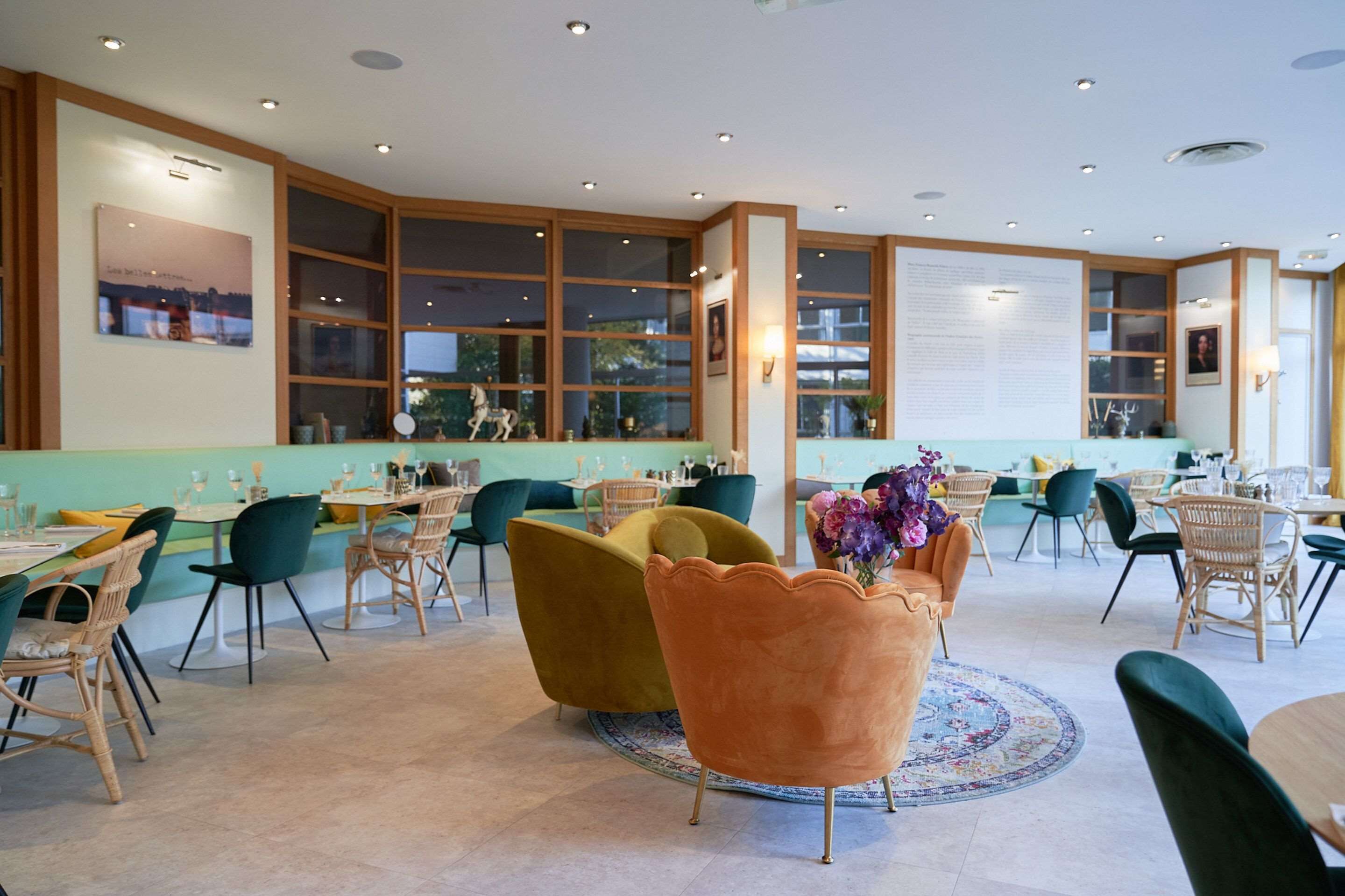 Un restaurant spacieux avec de hauts plafonds, de grandes fenêtres et différents types de sièges, notamment des chaises et des tables.