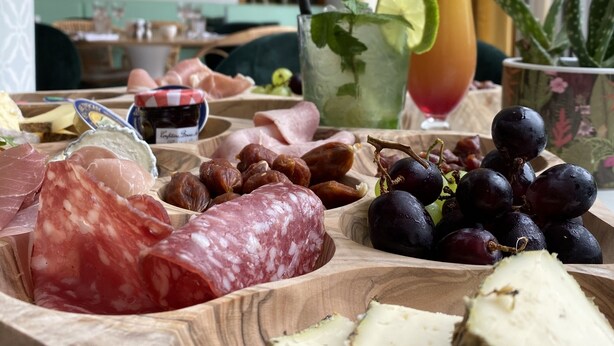 Une planche en bois garnie de différents fromages, de charcuteries et de fruits.