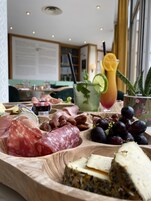 Una tabla de madera con varios quesos, embutidos y frutas.