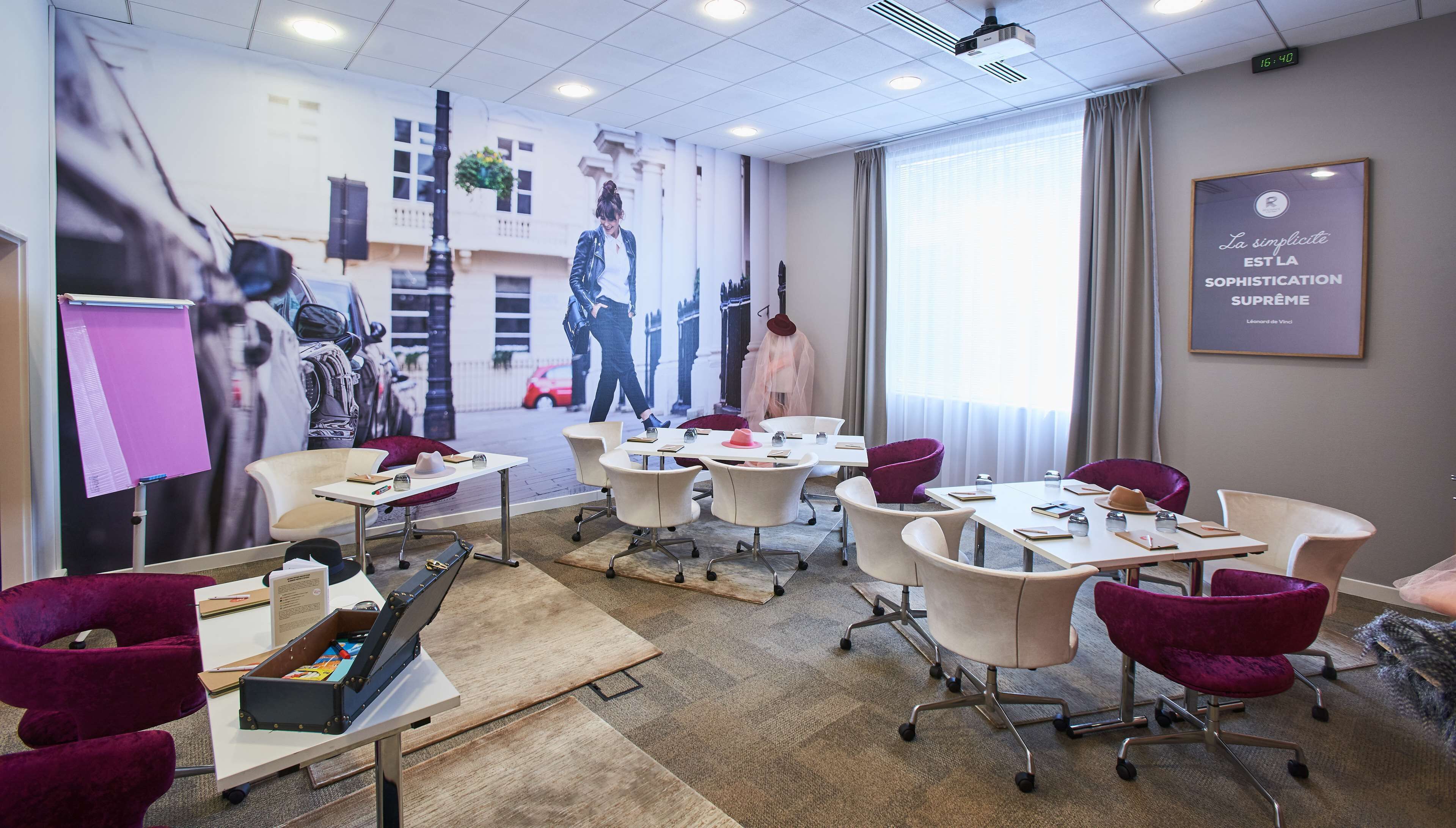 A conference room with tables, chairs, and a projector screen.