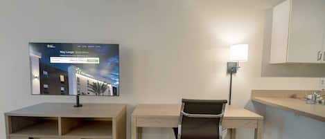 Une chambre d’hôtel équipée d’un bureau, d’une chaise, d’une télévision et d’une lampe.