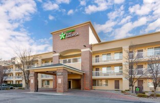 Un hotel de varios pisos con un llamativo letrero de Extended Stay America, un área de recepción y un estacionamiento.