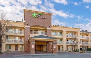Un hotel de varios pisos con un llamativo letrero de Extended Stay America, una entrada al vestíbulo y un área de estacionamiento.