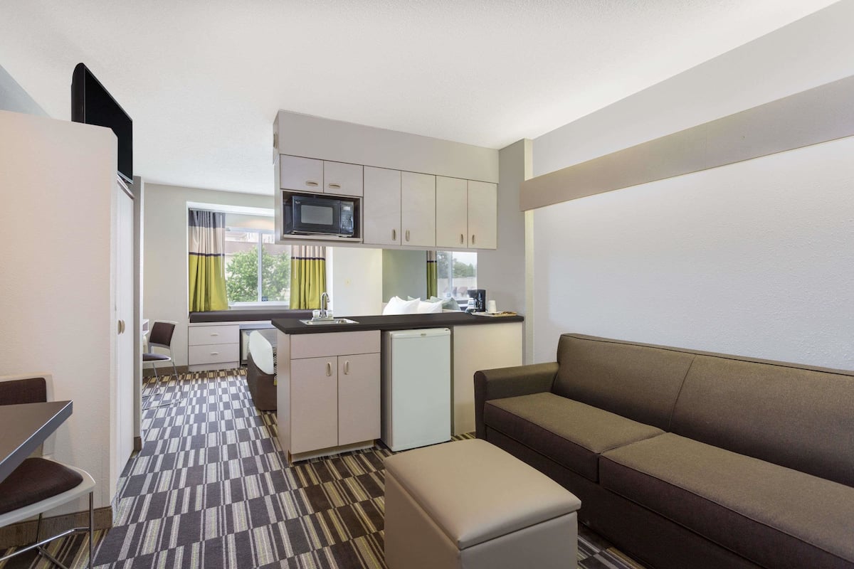 Une chambre d’hôtel compacte comprenant un coin cuisine, un canapé et un espace repas.