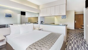 A hotel room with a large bed, a small kitchenette, a mirror, and a bathroom. - Microtel Inn & Suites by Wyndham Richmond Airport (Sandston)