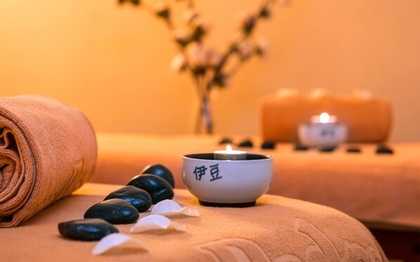 A spa setting with a towel, stones, and candles. - Dom Pedro Lisboa Hotel, a member of Radisson Individuals (Lisbon)