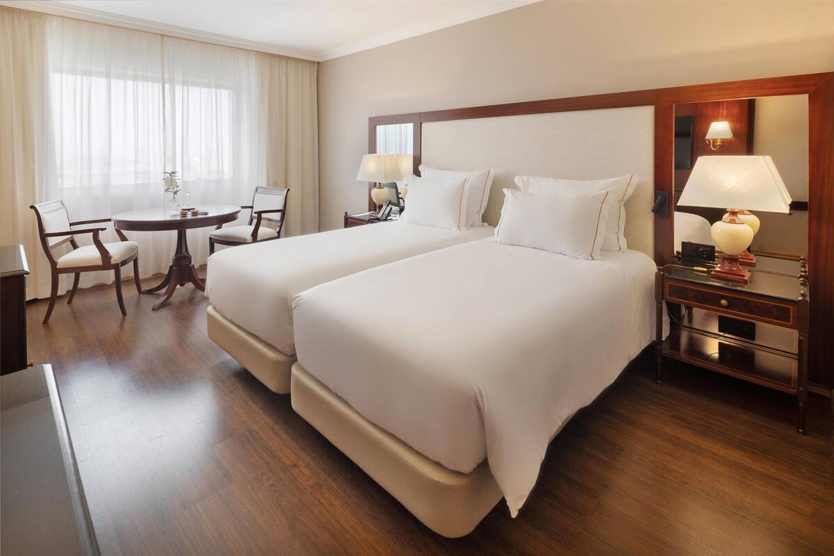 Habitación de hotel con dos camas, un escritorio, sillas y una mesa.