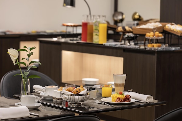 Un buffet de petit-déjeuner proposant une variété d’aliments, un coin café et un bar à jus.