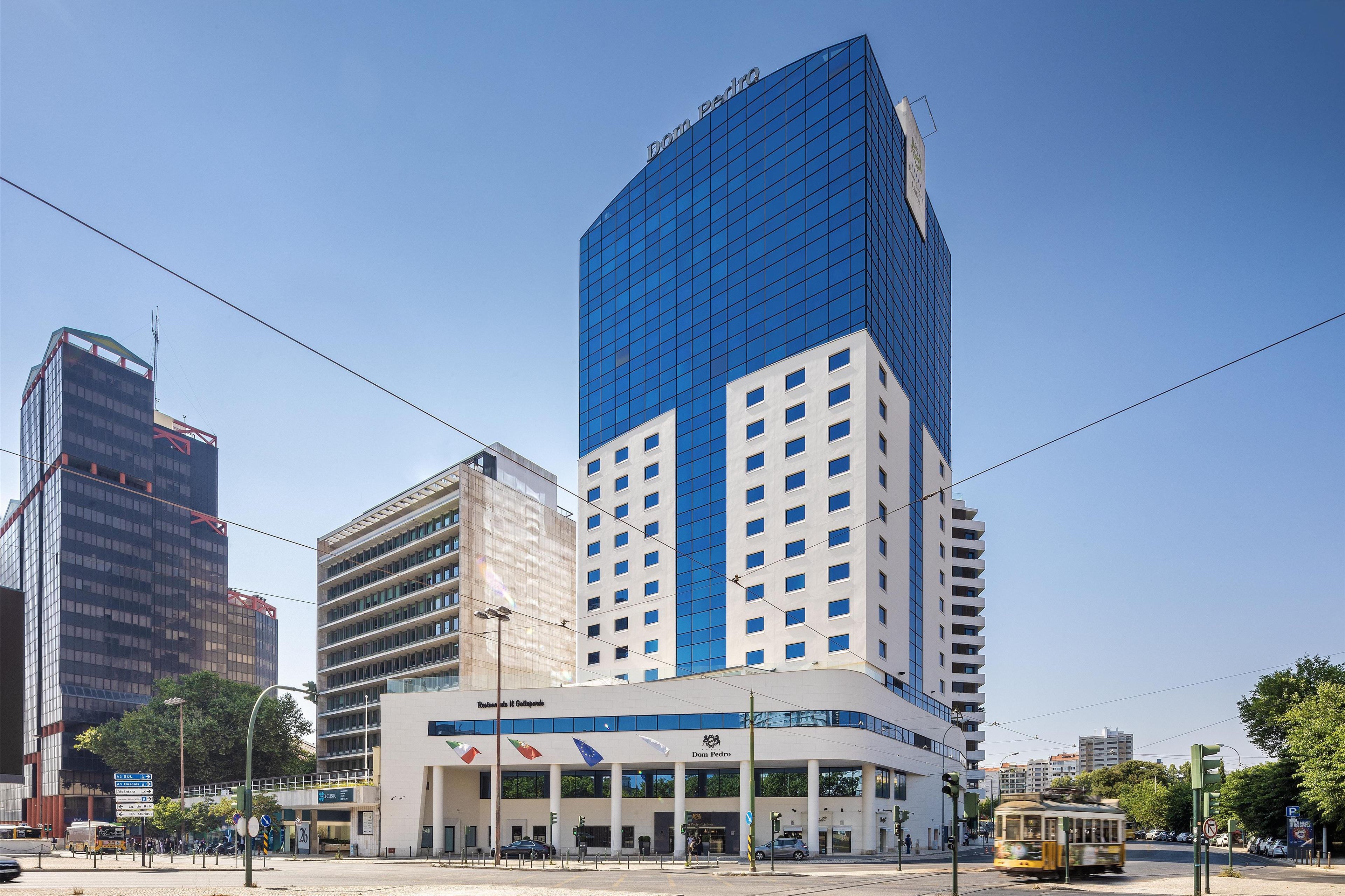 A modern building with a prominent blue glass facade and a sign reading "Dom Pedro."