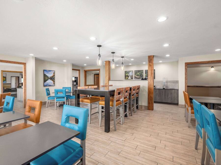 A modern dining area with wooden flooring, blue and brown chairs, and a central table.