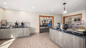 A modern kitchen area with a buffet setup, including a coffee machine, a toaster, and a food display.