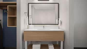 A modern bathroom with a wooden vanity, a large mirror, and a shelf with folded towels.