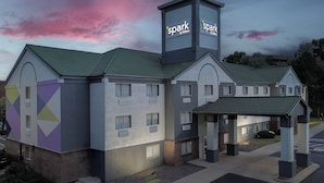 Een hotel met een modern design, met een opvallend ‘spark by Hilton’ bord, een overdekte ingang en een parkeerplaats.