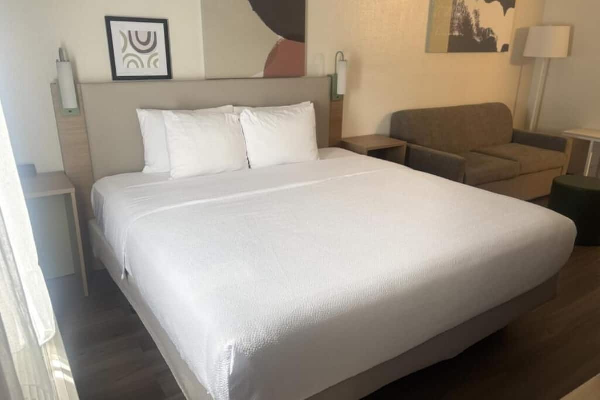 Ein Hotelzimmer mit einem großen Bett, einer Couch, einem Nachttisch und einer Lampe.