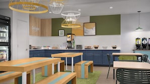 Een moderne keuken met houten tafels en banken, een koffieapparaat en een koelkast.