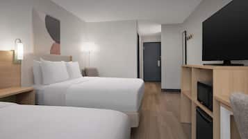 Una habitación de hotel moderna con dos camas, una televisión de pantalla plana, un microondas y un refrigerador pequeño.