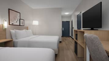 A hotel room with two beds, a TV, a desk, and a chair.