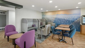 Un'area lounge moderna con posti a sedere, un tavolo in legno e un murale al muro.