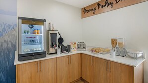 Angolo colazione con frigorifero, tostapane, macchina per il caffè e distributori di cereali.