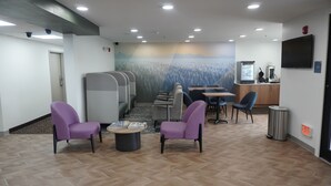 Una hall d'hotel con zone relax, una reception e un murale.