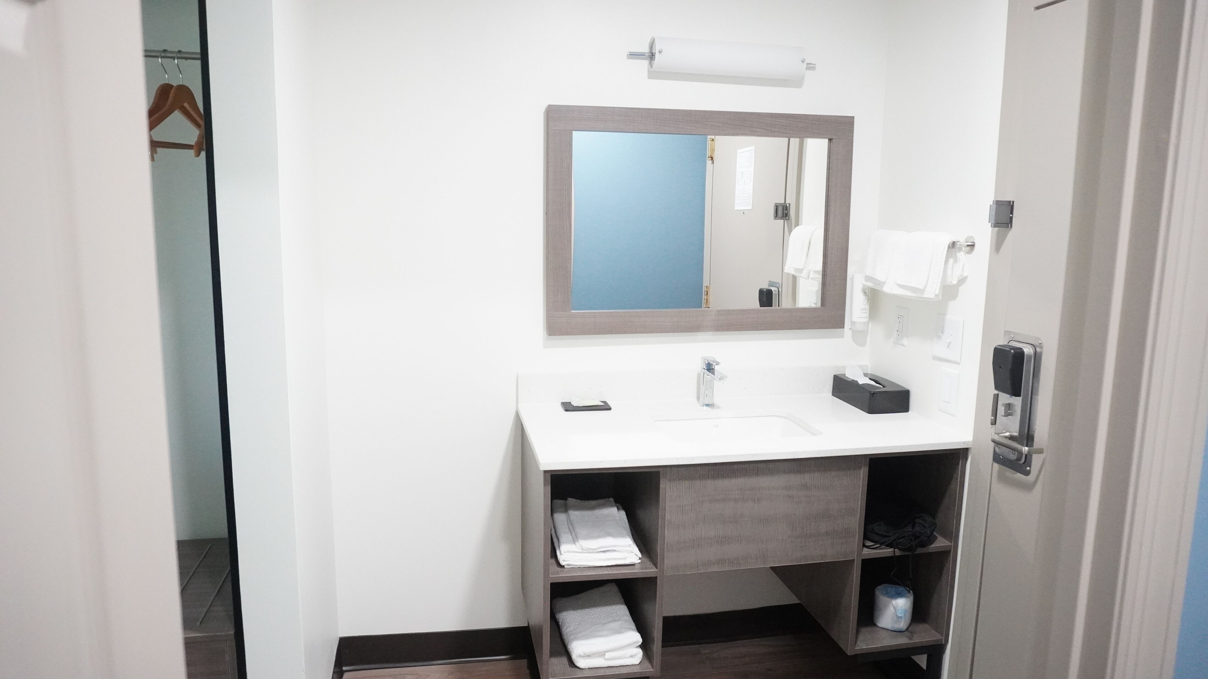 A modern bathroom with a white sink, a mirror, and a towel rack.