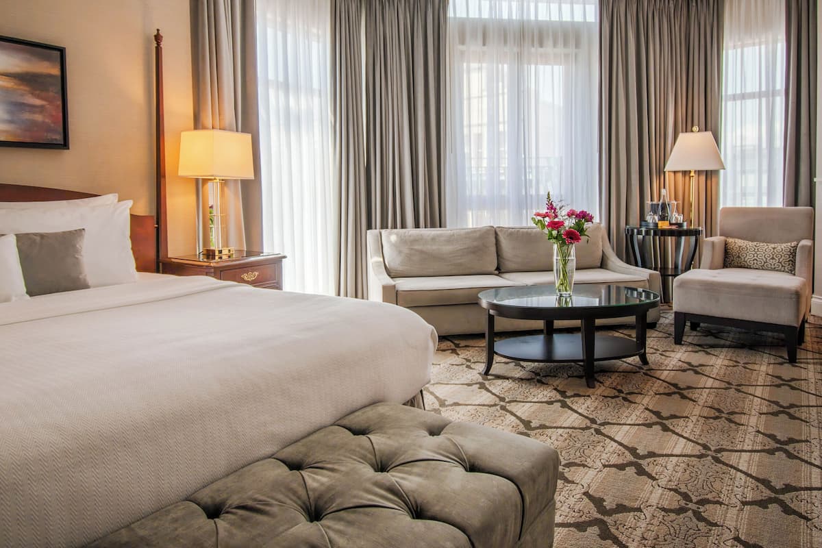 Una habitación de hotel con una cama grande, un sofá, una mesa de centro redonda y una silla.