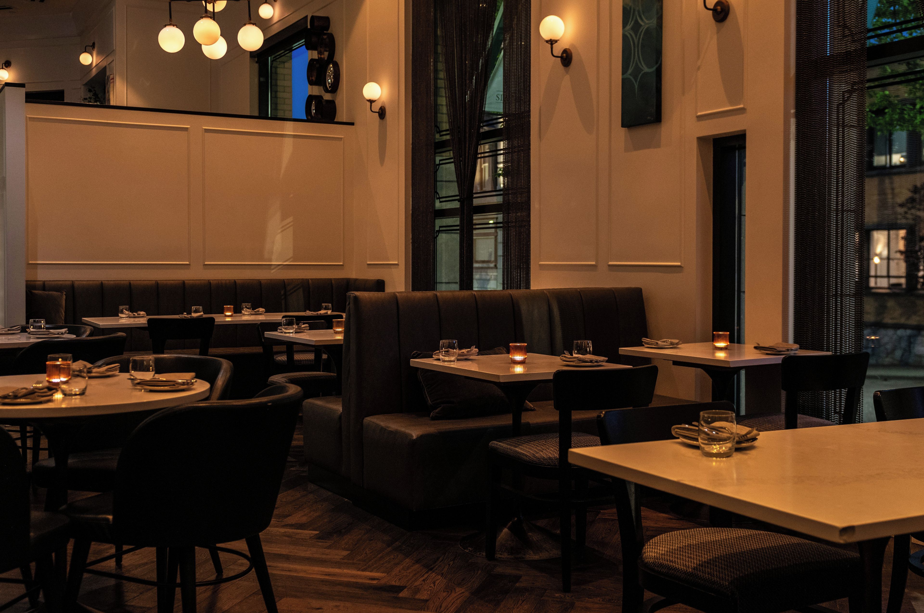 A restaurant interior with booths, tables, and hanging light fixtures.