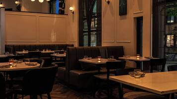 A restaurant interior with booths, tables, and hanging light fixtures.