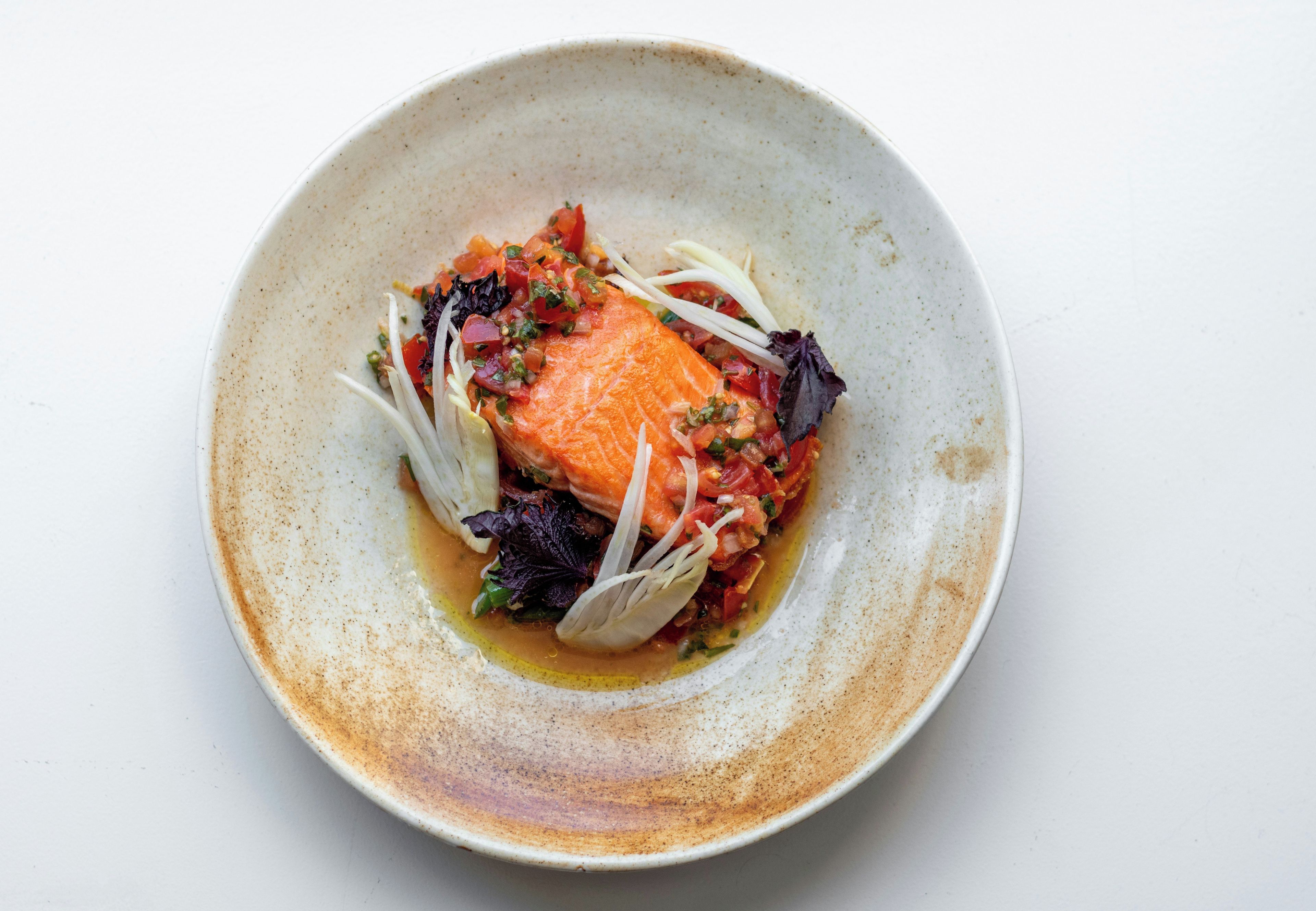 A plate with salmon, vegetables, and a sauce.