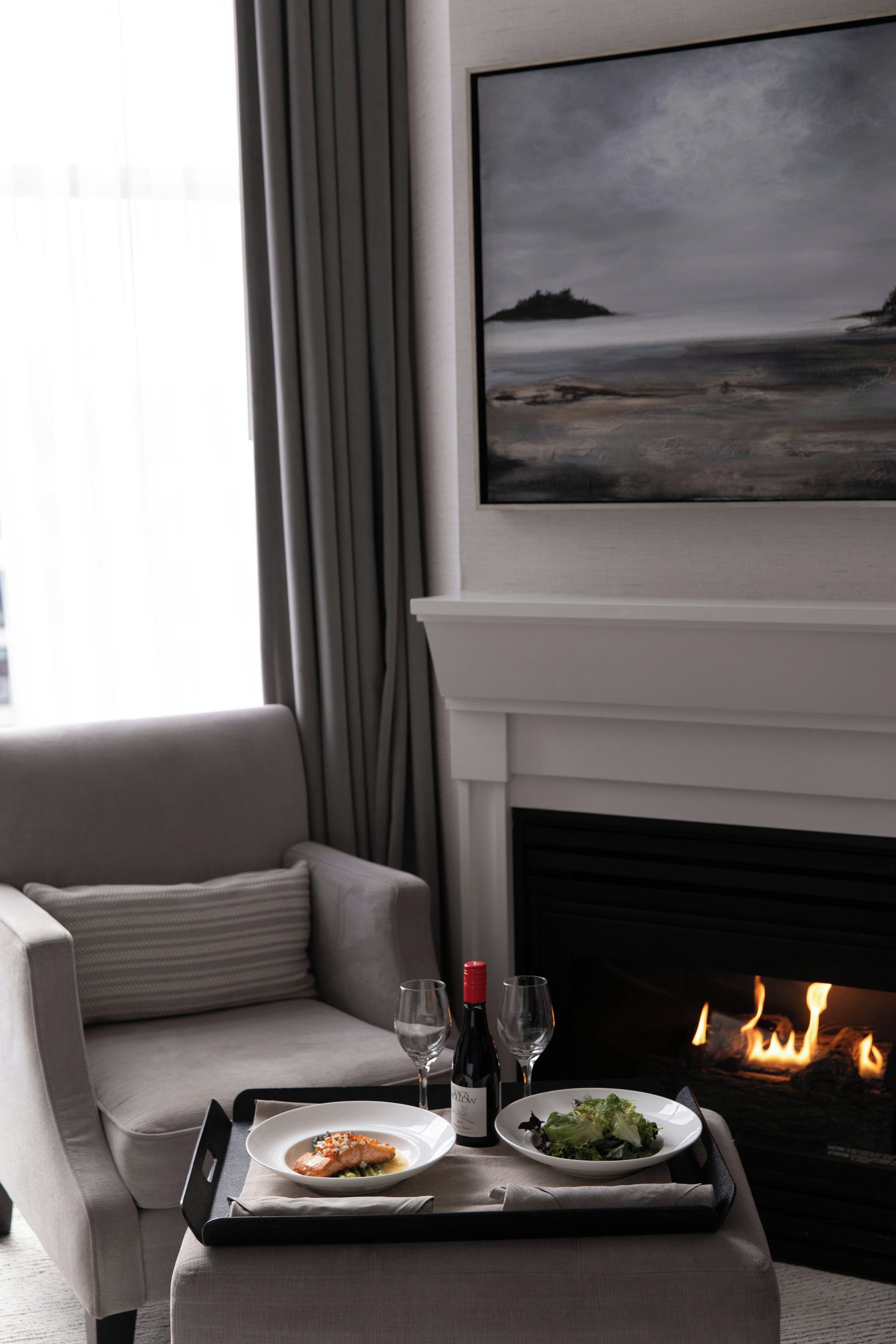 A dining area with a fireplace, a painting of a landscape, and a sofa.