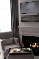 A dining area with a fireplace, a painting of a landscape, and a sofa.