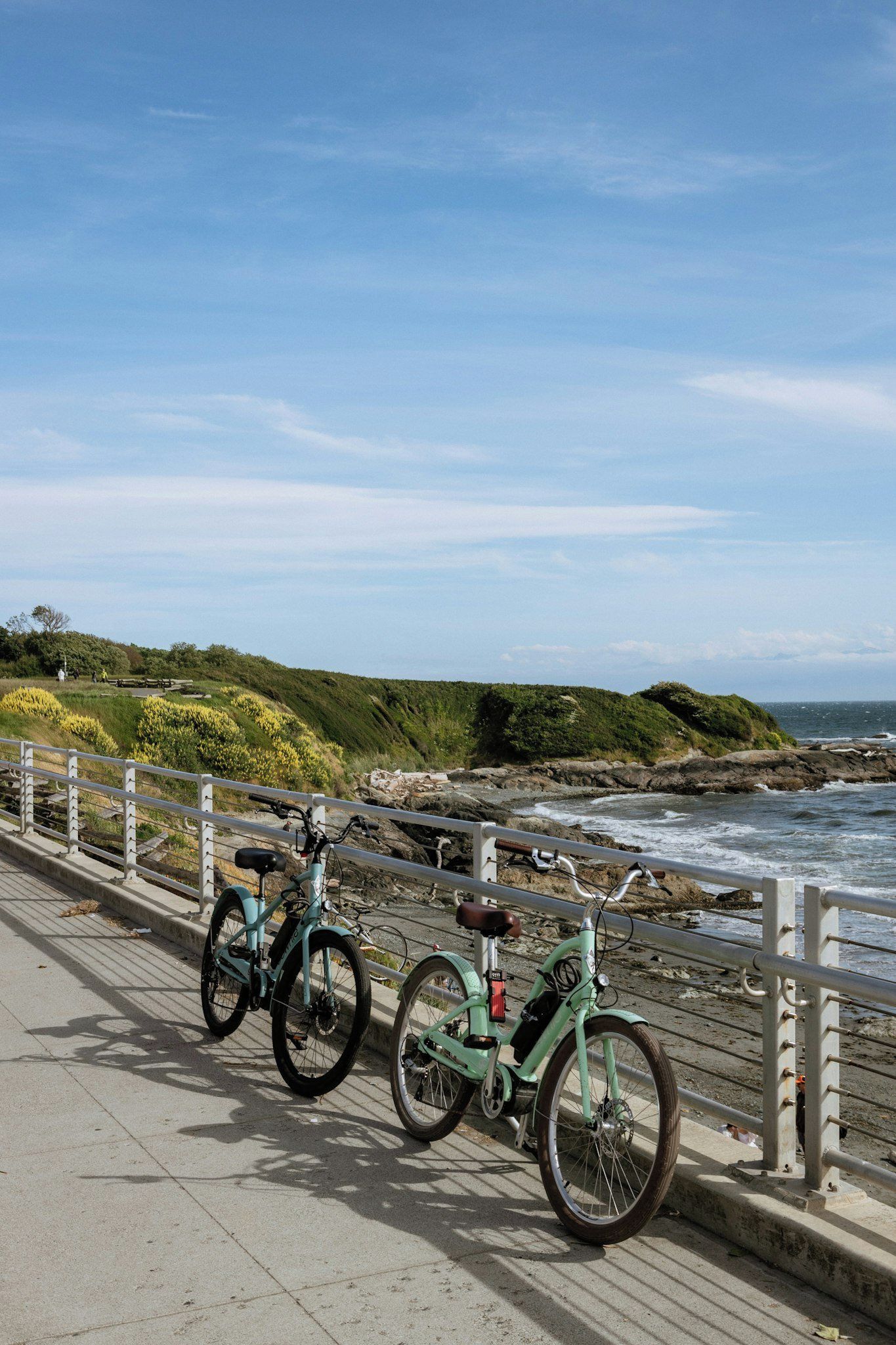 A coastal walkway with bicycles parked along the railing.