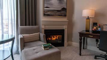 A hotel room with a fireplace, a sofa, a table, and a lamp.