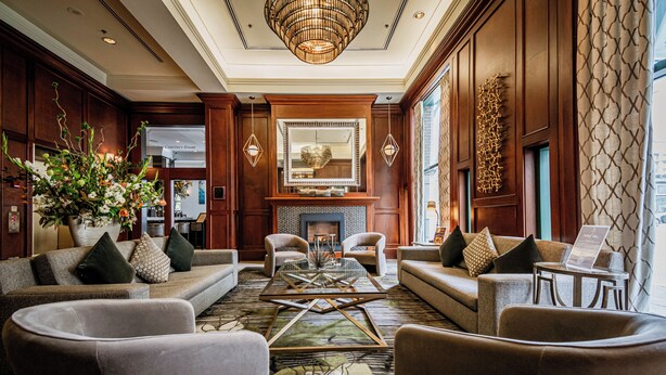 A spacious lobby with a large seating area, a fireplace, and a chandelier.