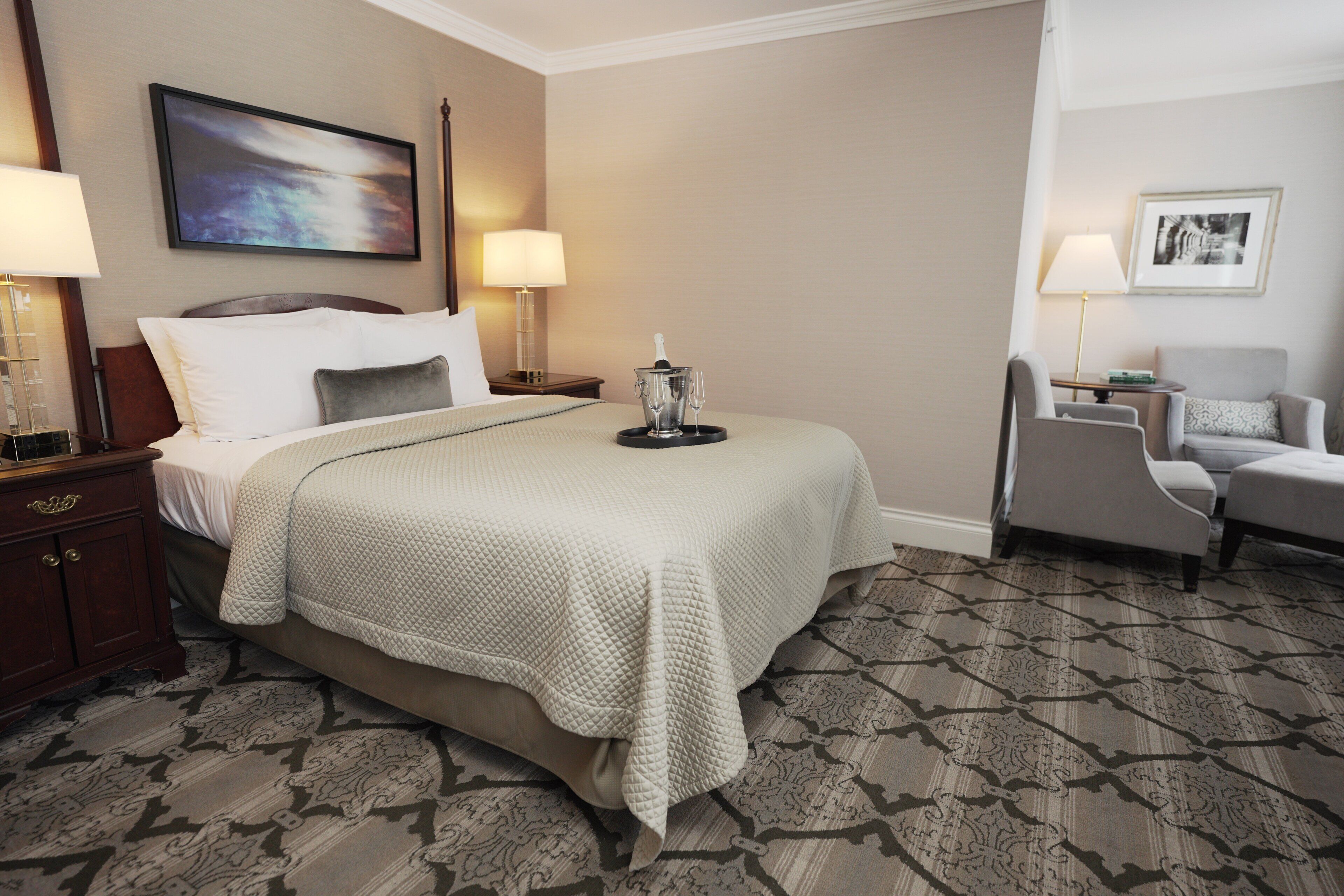 A hotel room with a bed, nightstands, a chair, and a carpeted floor.