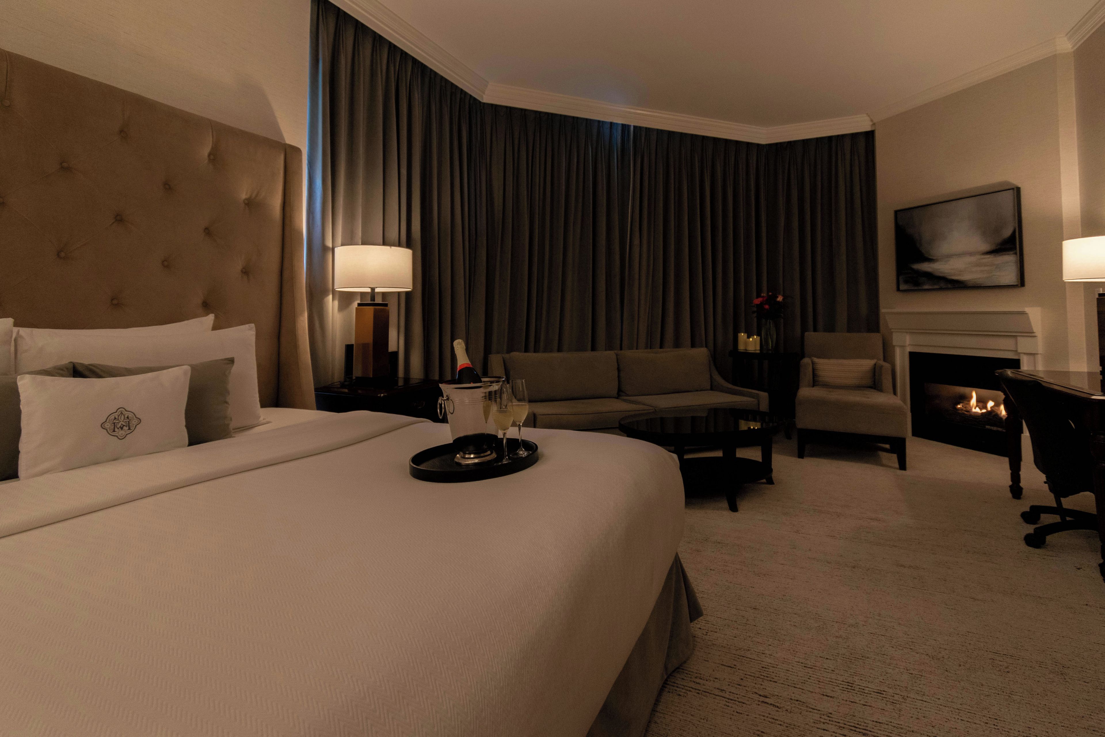 Une chambre d’hôtel avec un grand lit, un canapé, une table basse, une cheminée et un téléviseur.