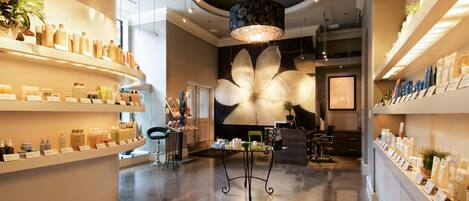 A spacious lobby with a large floral mural, a reception desk, and shelves displaying various products.