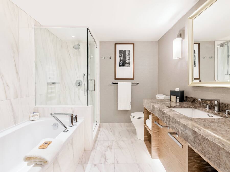 A modern bathroom with a large bathtub, a shower area, and a vanity with two sinks.