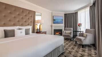 Une chambre d’hôtel avec un grand lit, une cheminée, deux fauteuils et un téléviseur.