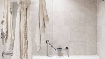 A bathroom with a bathtub, a towel rack with a robe, and a shower head.