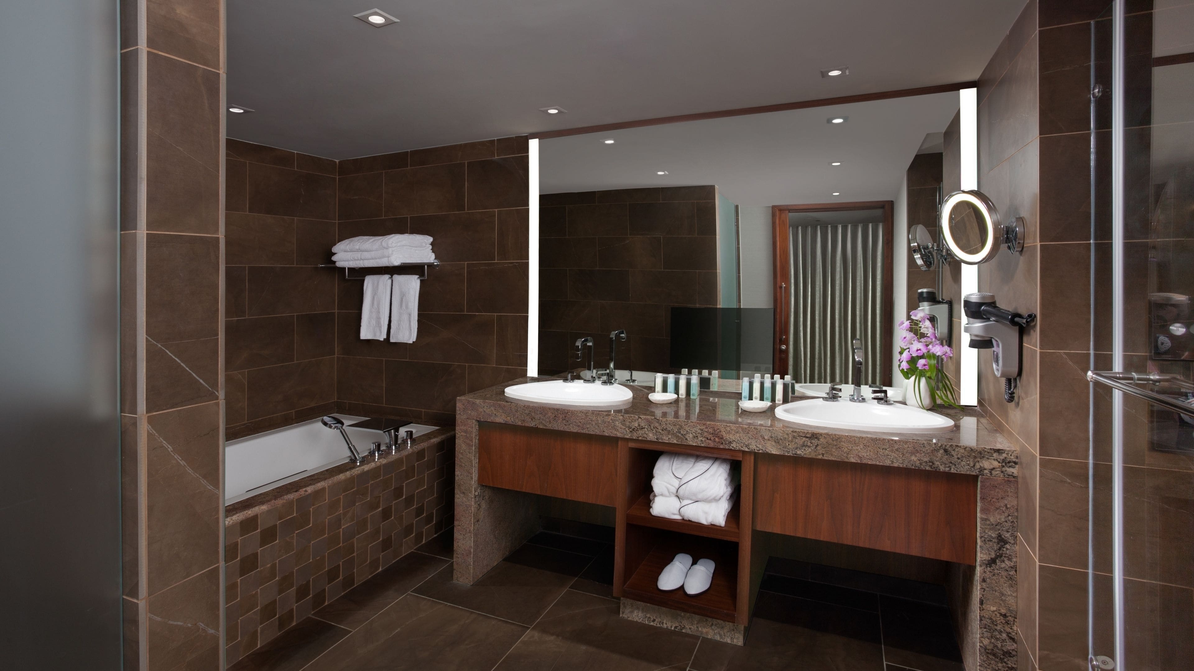 Un baño moderno con dos lavamanos, una bañera y un espejo grande.