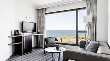A modern hotel room with a large window offering a view of the beach and ocean.