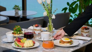 Une table dressée avec différents plats, des boissons et un vase de fleurs, probablement dans un restaurant ou un café.