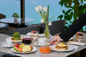 Ein Tisch ist reichhaltig mit Speisen, Getränken und einem Blumenstrauß gedeckt, vermutlich in einem Restaurant oder Café.