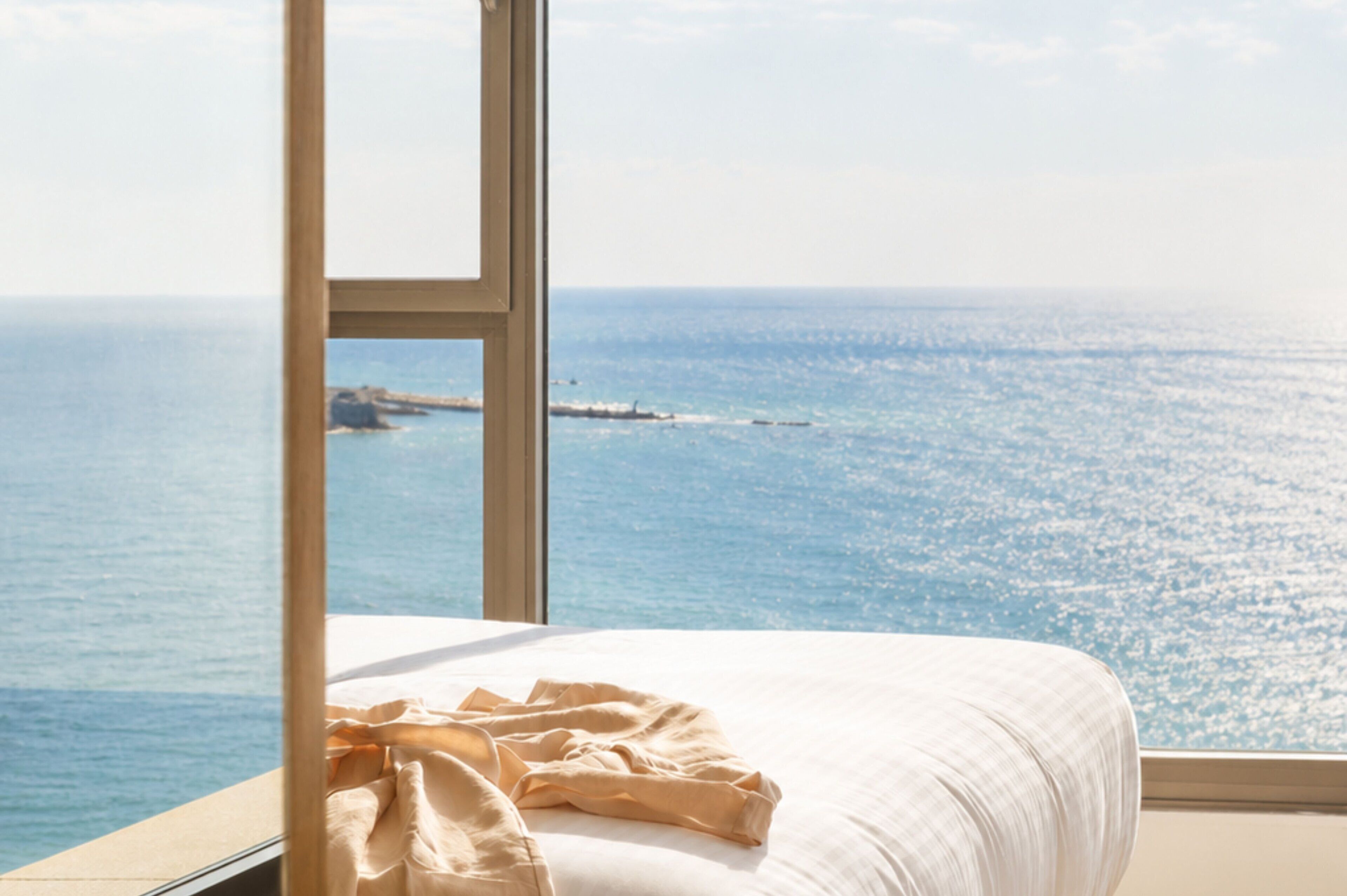 Una cama con vista al mar a través de una ventana.
