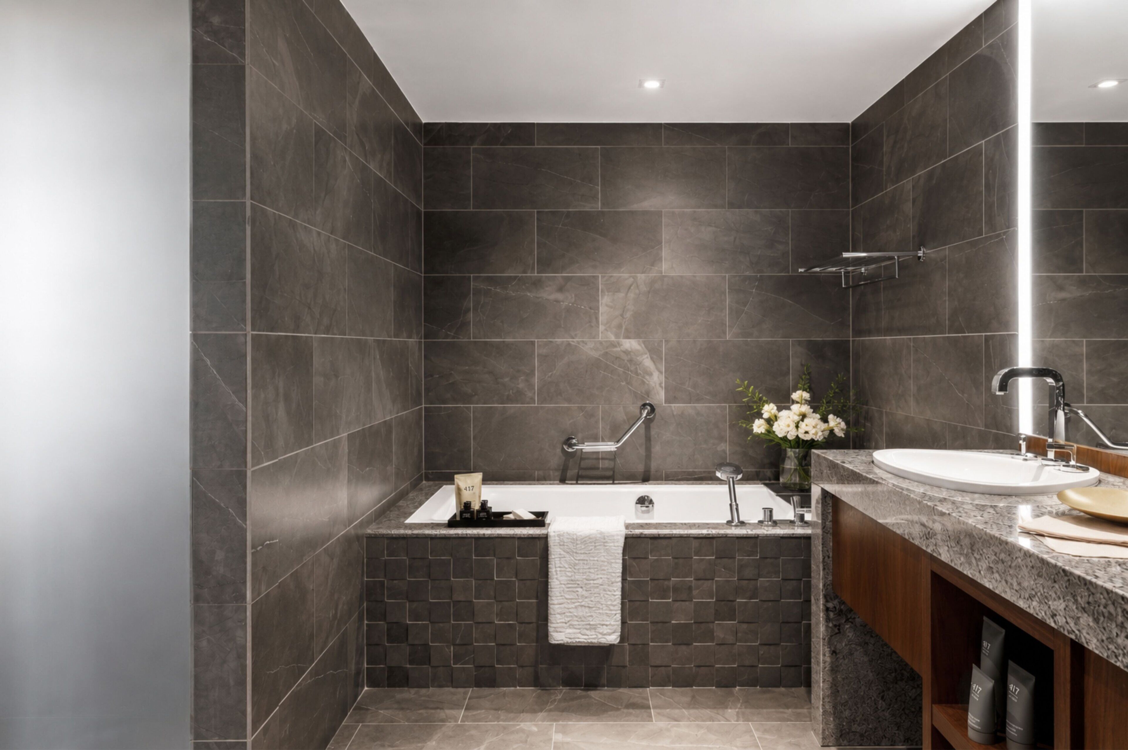 A modern bathroom with a freestanding bathtub, a vanity with a sink, and a towel rack.