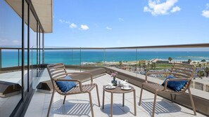 A balcony with two chairs and a small table, overlooking a beach and ocean. - InterContinental David Tel Aviv by IHG (Tel Aviv)