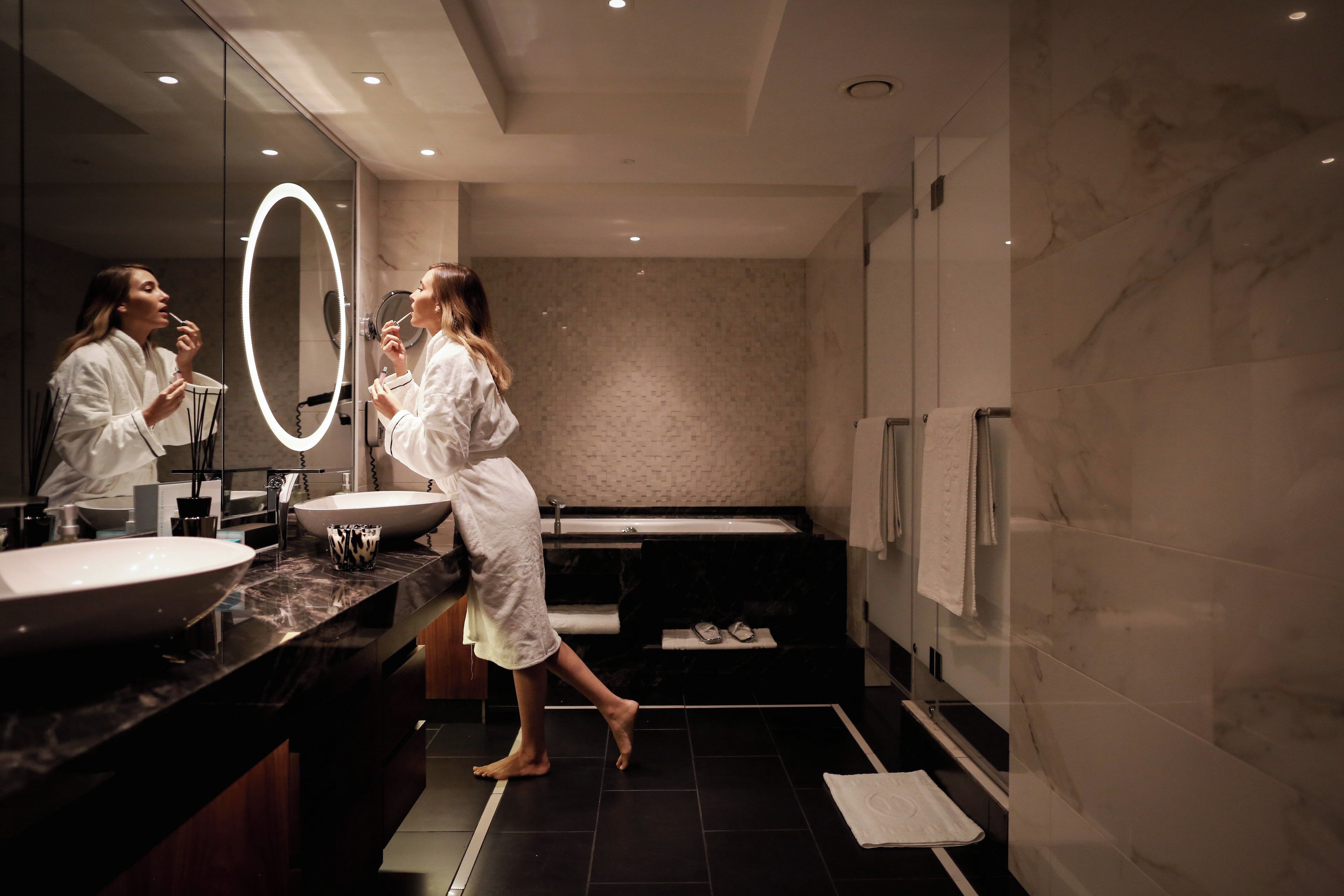Un baño moderno con un espejo grande, un lavabo y una bañera.