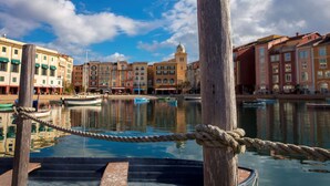 A waterfront scene with buildings, a wooden post, and a rope barrier. - Universal’s Loews Portofino Bay Hotel (Orlando)