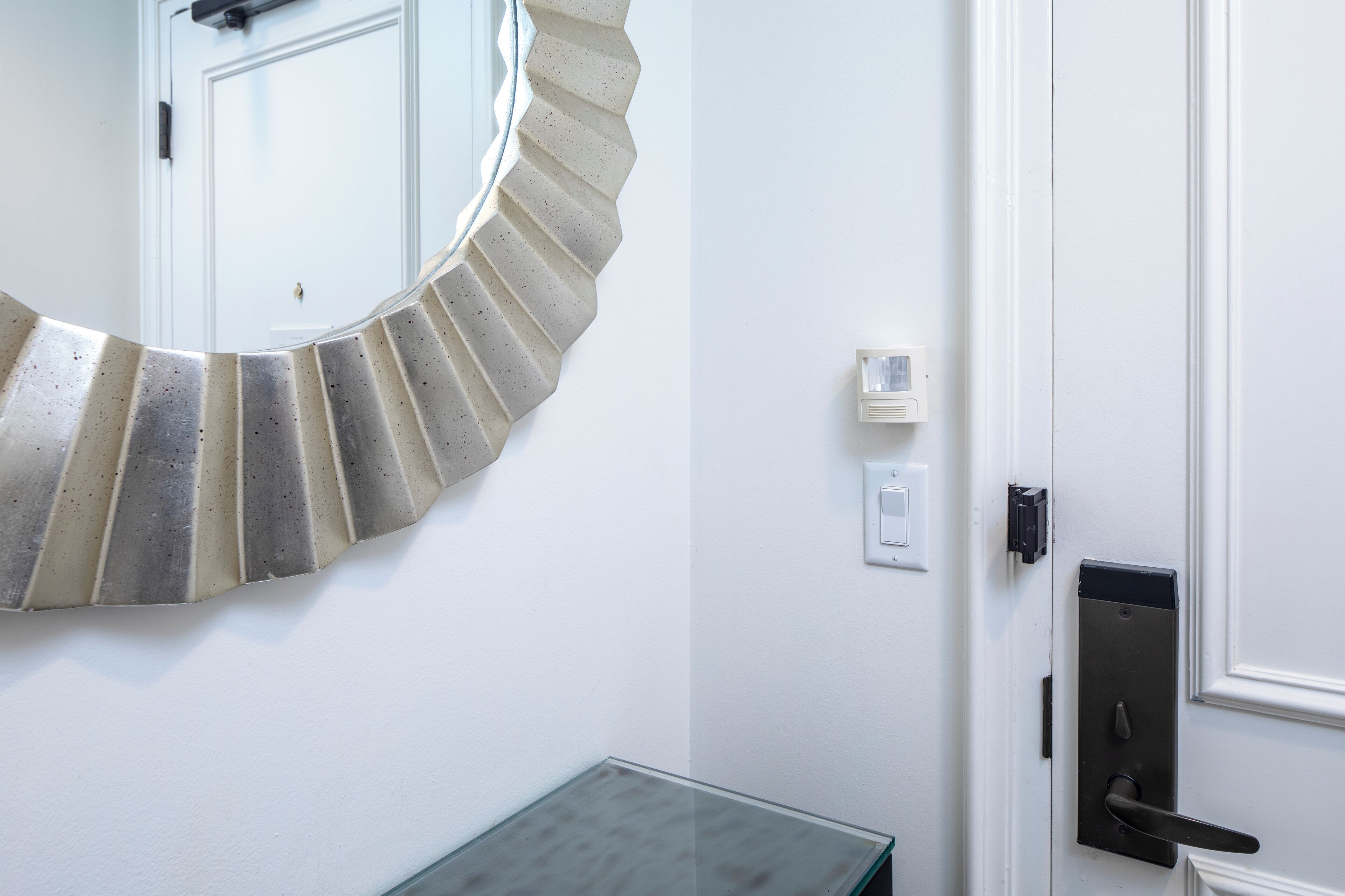 A modern bathroom with a curved mirror, a glass table, and a door with a handle.